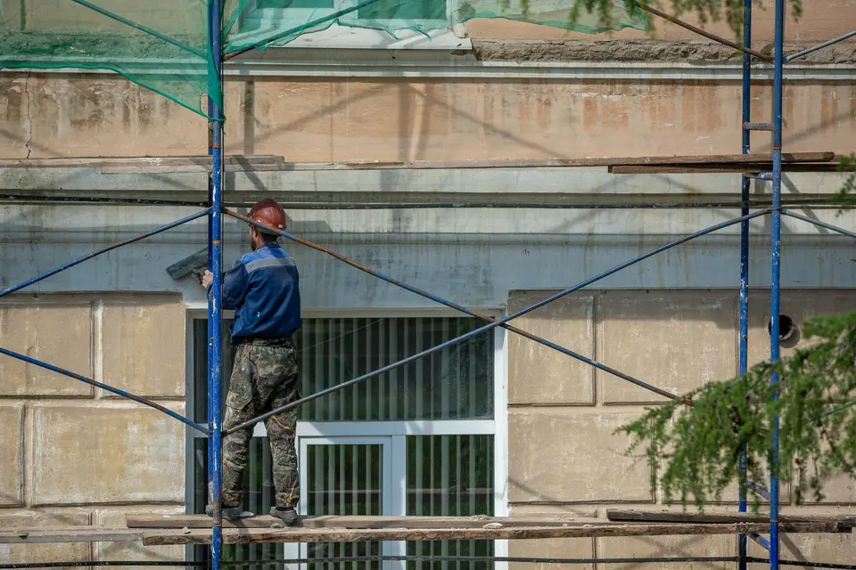 Ouvrier casqué sur un échafaudage devant une façade en réfection