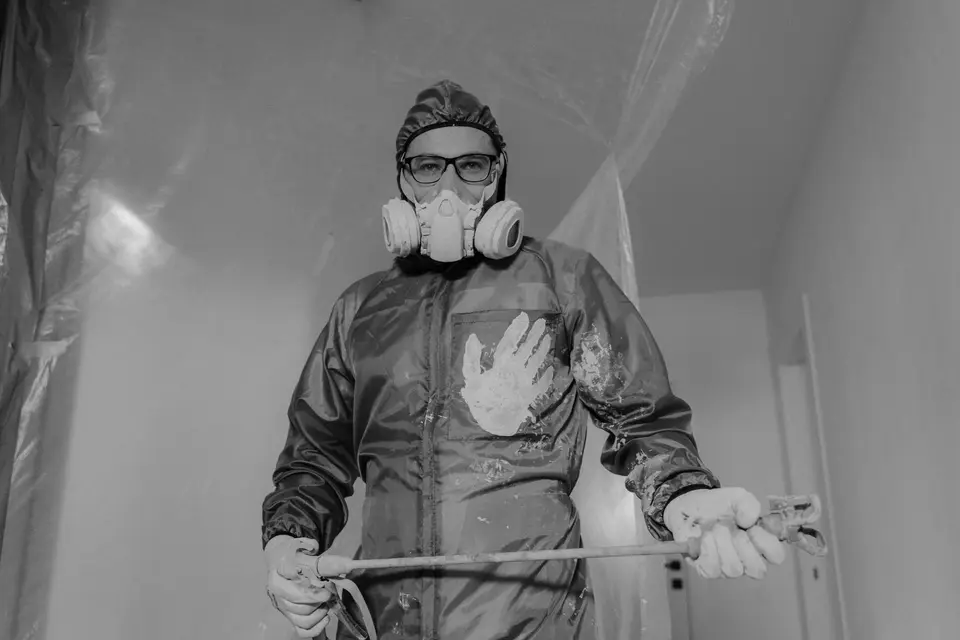 Intervenant en combinaison et masque respiratoire dans une pièce bâchée